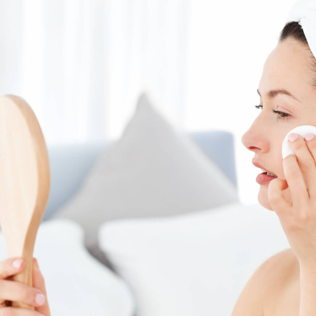 세안 후 거울을 보며 보습 크림을 바르고 있는 사진