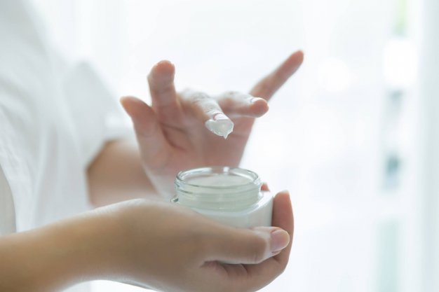 woman holds a jar with a cosmetic cream in her hands. skin care 스킨 케어 제품을 손가락에 찍어 바르는 사진